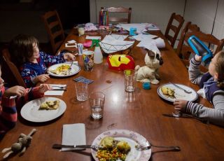 Dzieci jedzą kolację wśród zabawek