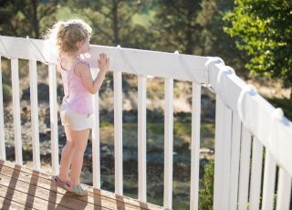 Dziewczynka stoi na tarasie przy barierce