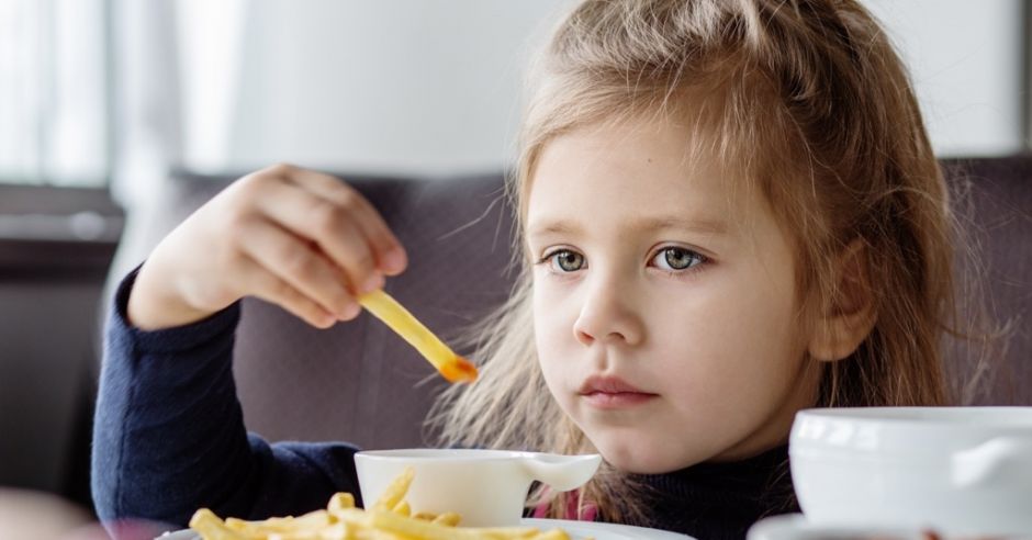 dziewczynka w restauracji je frytki