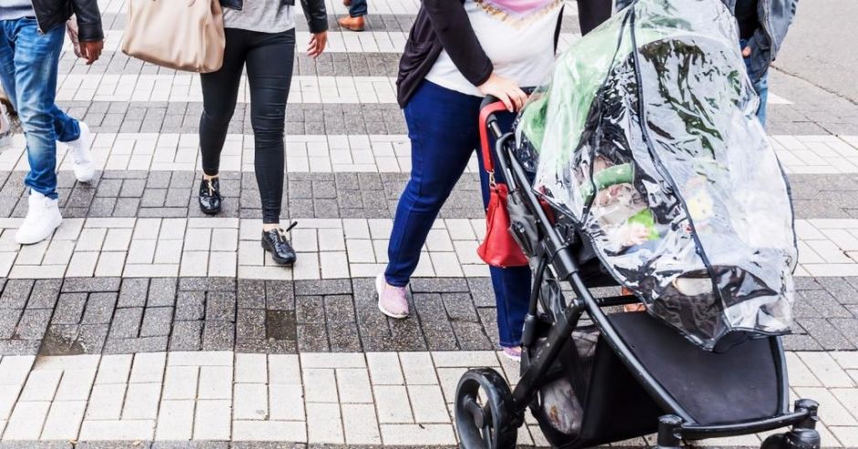 Kobieta prowadzi wózek na przejściu dla pieszych