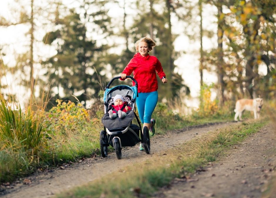mama na spacerze w lesie biega z dzieckiem w wózku i psem