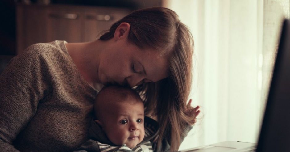 Mama pracuje zdalnie z dzieckiem na kolanach