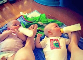 Matka karmi bliźnięta przytrzymując butelki stopami