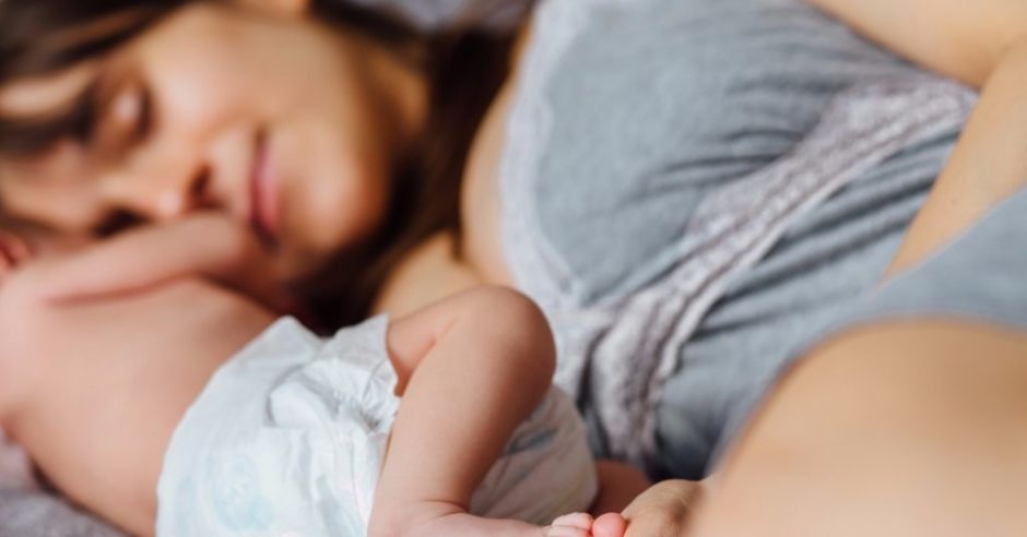 Młoda mama na urlopie rodzicielskim leży z niemowlakiem