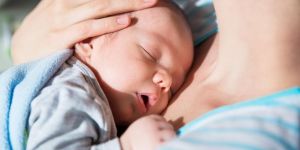 Niemowlę śpi u mamy na rękach