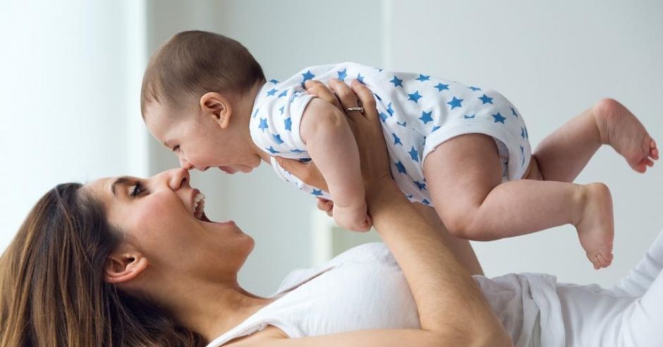 Uśmiechająca się mama bawi się z niemowlakiem
