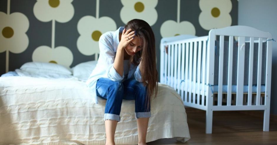 Zmęczona młoda mama siedzi na łóżku